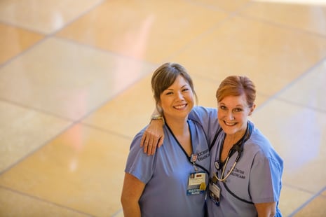 Two smiling nurses with their arms around each other